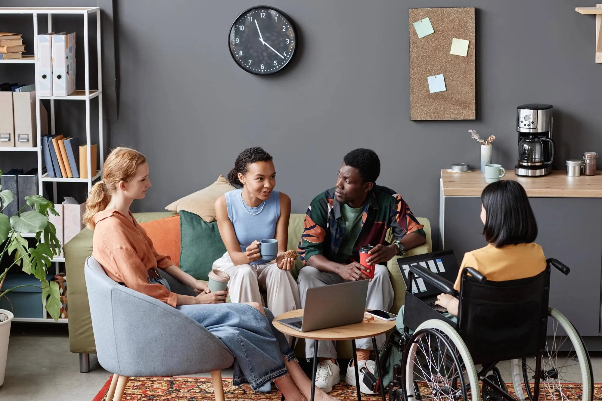 Four adults, one using a wheelchair, talking together in a relaxed lounge
